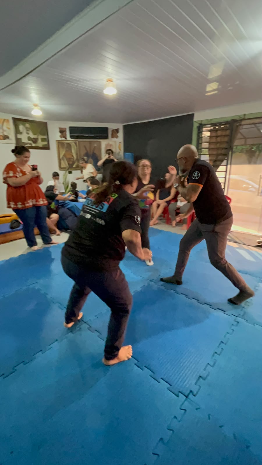Professor Vermelho conduzindo uma vivência de capoeira com participantes e familiares
