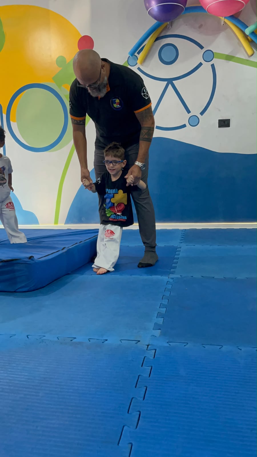 Professor Vermelho apoiando uma criança durante uma experiência de movimento