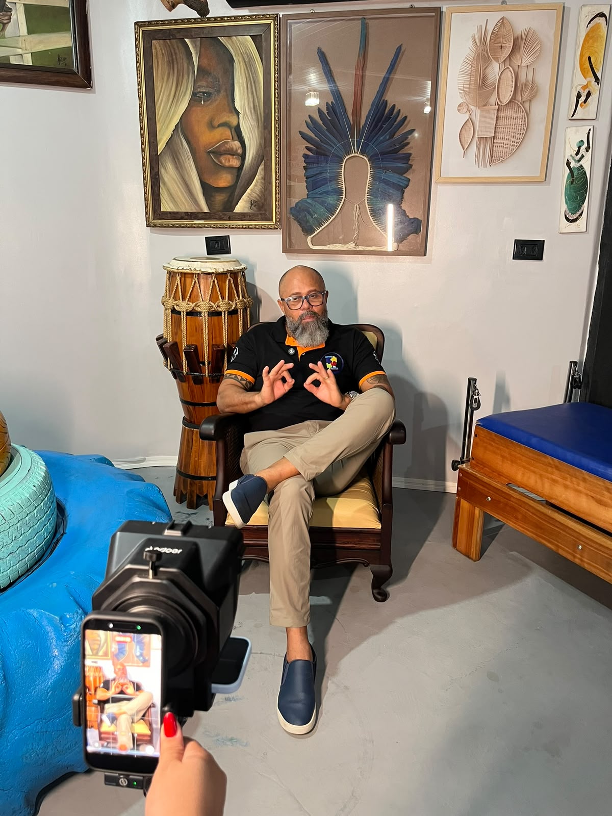 Professor Vermelho em entrevista diante de obras e instrumentos da cultura brasileira